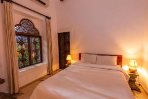 a bedroom with a bed and a stained glass window at Marbella Guest House in Sinquerim