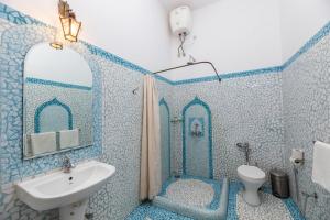 a blue tiled bathroom with a sink and a toilet at Marbella Guest House in Sinquerim