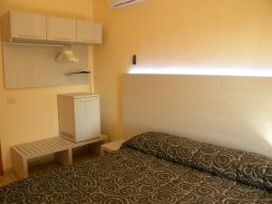a small room with a bed and a small refrigerator at Hotel Rosa Del Tirreno in Quercianella