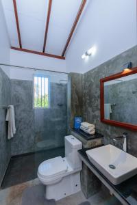 a bathroom with a toilet and a sink and a mirror at Villa Guru Hikkaduwa in Hikkaduwa
