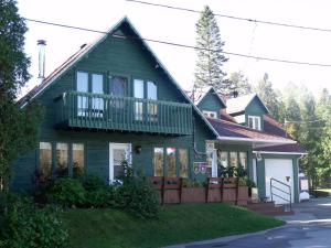 a green house with a balcony on top of it at Camping Le 4 Chemins in LʼAnse-Saint-Jean