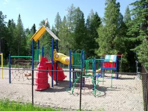 een speeltuin met kleurrijke speeltoestellen in een park bij Camping Le 4 Chemins in LʼAnse-Saint-Jean