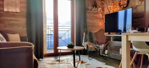 a living room with a tv and a desk with a table at Apartment F10 Milmari Resort in Kopaonik