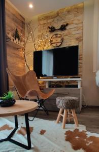 a living room with a tv and a chair and a table at Apartment F10 Milmari Resort in Kopaonik