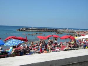 a crowd of people on a beach with red umbrellas at Hotel Rosa Del Tirreno in Quercianella