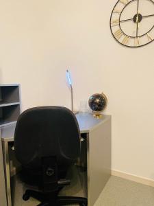 een bureau met een stoel en een klok aan de muur bij Blagnac Toulouse Like at home in Blagnac
