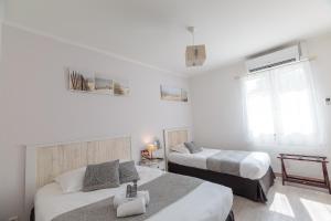 a white bedroom with two beds and a window at Le Heron Cendré in La Tremblade