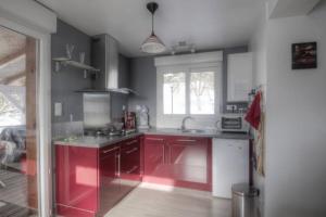 una cucina con armadi rossi e una grande finestra di L'ATELIER, chalet 3* a Vecoux