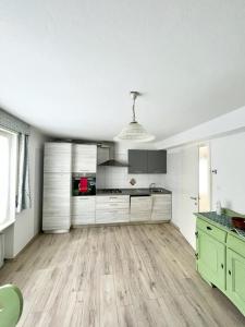 a large kitchen with white cabinets and a wooden floor at SUITE DOLOMITI Appartamento in Falcade