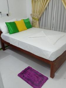 a bed with white sheets and colorful pillows in a room at lake Edge Dambulla in Dambulla