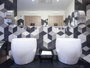 a bathroom with black and white tiles and two toilets at Motel L Hammarby Sjöstad in Stockholm