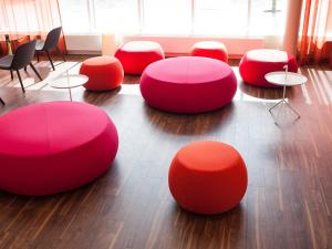 a group of red chairs and tables on a floor at Motel L Hammarby Sjöstad in Stockholm