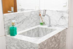 a bathroom with a sink with a bottle of soap at Aconchego in Maringá +14 photos