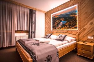 a hotel room with a bed and a painting on the wall at Willa Grań Jacuzzi & Sauna in Kościelisko