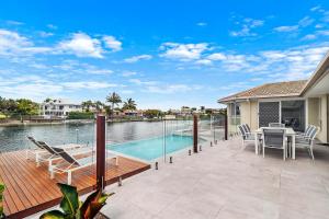 a patio with a table and chairs and a swimming pool at Breathtaking 4BR Resort like House Right Near Wurtulla Beach With Infinity Pool in Kawana Waters