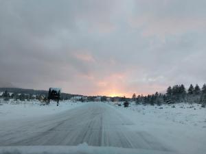 a snow covered road with the sunset in the background at Vikendica Pinus Blidinje in Blidinje +2 photos