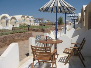Lagona Dahab Hotel في دهب: طاولة وكراسي ومظلة على الفناء
