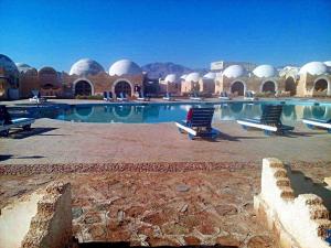 una piscina con sedie e edifici a cupola di Lagona Dahab Hotel a Dahab
