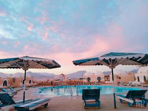 una piscina con sedie e ombrelloni di fronte a un resort di Lagona Dahab Hotel a Dahab