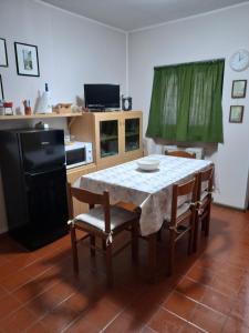 cocina con mesa con sillas y nevera negra en Monolocale cimarosa, en Caspoggio
