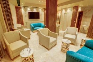 una sala de espera con sillas, mesas y TV en Turquoise Hotel, en Áqaba