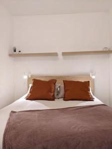 un grande letto con cuscini marroni e bianchi di Séjour cocooning pour se ressourcer à la montagne. ad Aulus-les-Bains Altre 7 foto