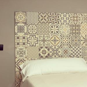 a bedroom with a bed with a wall covered in tiles at Belmonte Rooms in Gijón