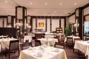 un restaurante con mesas y sillas con mantel blanco en Wyndham Duisburger Hof, en Duisburg