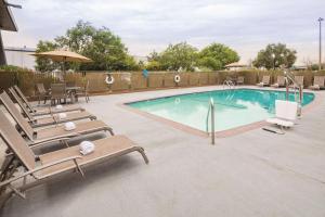 a swimming pool with lounge chairs and an umbrella at La Quinta by Wyndham San Jose Airport in San Jose