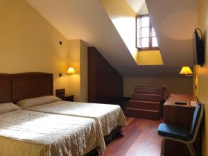a bedroom with a bed and a window and a chair at Hotel Aroi Bierzo Plaza in Ponferrada