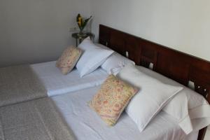 Cama con sábanas y almohadas blancas en Apartamento Bohemia, en Villanueva de Arosa