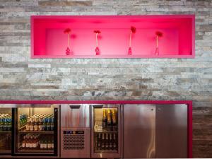 a pink wall in a bar with bottles of wine at Motel L Hammarby Sjöstad in Stockholm