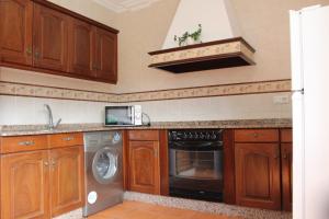 a kitchen with wooden cabinets and a dishwasher at Apartamento Bohemia in Villanueva de Arosa