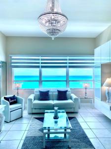 ein Wohnzimmer mit einem Sofa und einem Kronleuchter in der Unterkunft Large luxurious direct ocean front Penthouse or Deluxe one bedroom ocean front condo-free parking in Miami Beach