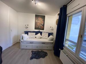 a room with a white couch with pillows and a window at Appartement Esplanade in Strasbourg
