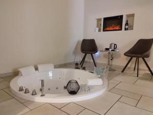 a bath tub in a room with two chairs and a tv at Lux Suite in Taranto