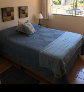 a bedroom with a bed with a blue blanket and a window at Edificio Club del Mar in Punta del Este