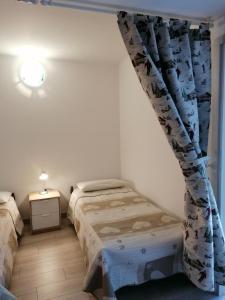 リモーネ・ピエモンテにあるCabanaira appartamentoのベッドルーム1室(ベッド2台、カーテン付)