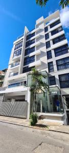 a tall white building with a palm tree in front of it at AMG Suites Apartment in Santo Domingo