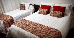 Duas camas com cobertores e almofadas vermelhos e brancos em Hotel Los Angeles em Gualeguaychú