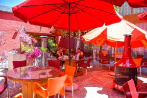 un patio con mesas, sillas y sombrillas rojas en CicloLodge, en Lozoya