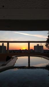 una puesta de sol sobre una piscina de agua con un puente en Hotel Los Angeles en Gualeguaychú