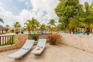 プンタ・カナにあるLuxe 1 BR Cap Cana, DR - Steps Away From Pool, King Bed, Caribbean Paradise!の白い椅子2脚とフェンス付きのパティオ