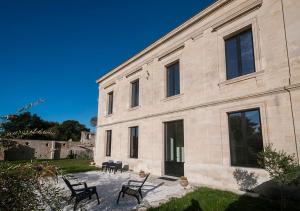 een groot stenen gebouw met stoelen ervoor bij Villa Courreau - Maison de maitre in Vendays-Montalivet