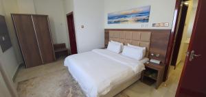 a bedroom with a large bed with white sheets at Al Deafah Hotel Apartment الضيافة للشقق الفندقية in Al Buraymī