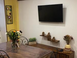 a dining room with a table and a television on the wall at En toute simplicité in Bielle