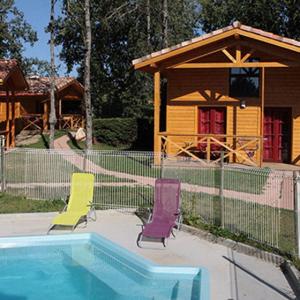 Fronton的住宿－Les gîtes des Palombes，两把椅子和一个位于房子前面的游泳池