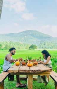 un hombre y una mujer sentados en una mesa de picnic con calabazas en Coconut Escapes en Kurunegala
