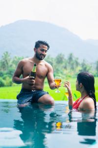 a man and a woman sitting in the water with a drink at Coconut Escapes in Kurunegala