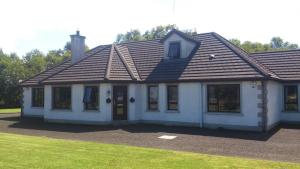 a small white house with a brown roof at Glen Lodge in Ballymoney